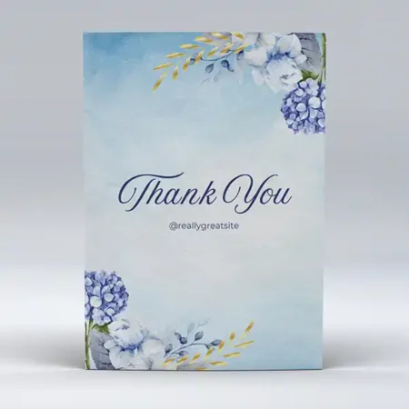 A thank you card with a light blue watercolor background, decorated with blue and white flowers and gold leaves, and with the text "Thank You" in a dark blue script.