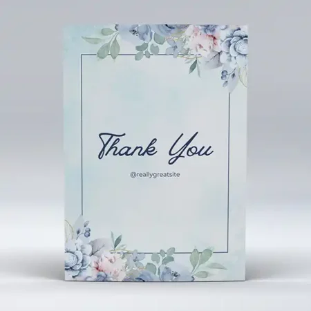 A thank you card with a light blue watercolor background, featuring a thin frame decorated with soft blue and pink flowers in the corners.
