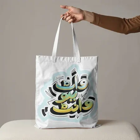 A white tote bag with a modern abstract Islamic calligraphy design