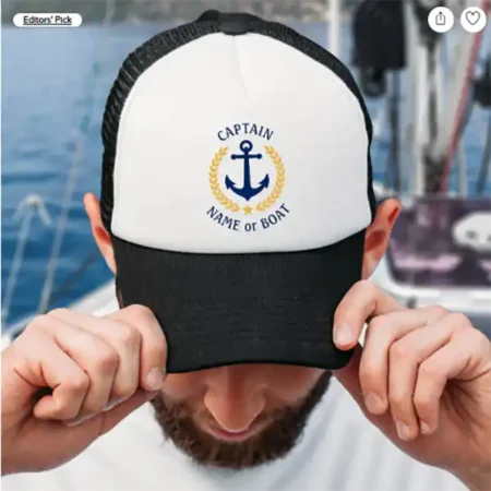 A man wearing a personalized black and white trucker cap with a nautical design featuring an anchor and the text "CAPTAIN" and "NAME or BOAT".